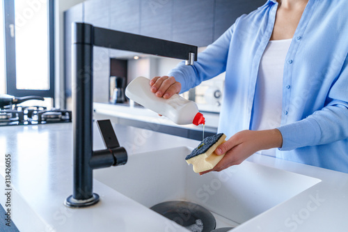 Housewife uses dishwashing detergent for wash up dishes in the kitchen at home