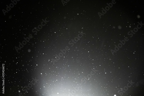 Snow and bokeh in the light of a lantern on a black background
