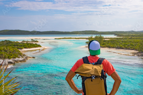Männlicher Tourist mit Rucksack schaut auf das tropische Meer in der Karibik, Long Island Bahamas