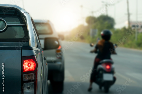 Luxury of pickup car stop on the junction by traffic light control in across. Traveling in the provinces during the bright period. Open light brake. with blurred image of motorcycle.