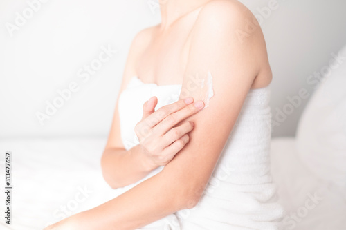 Woman applying arm cream,lotion on white bed, Hygiene skin body care concept...