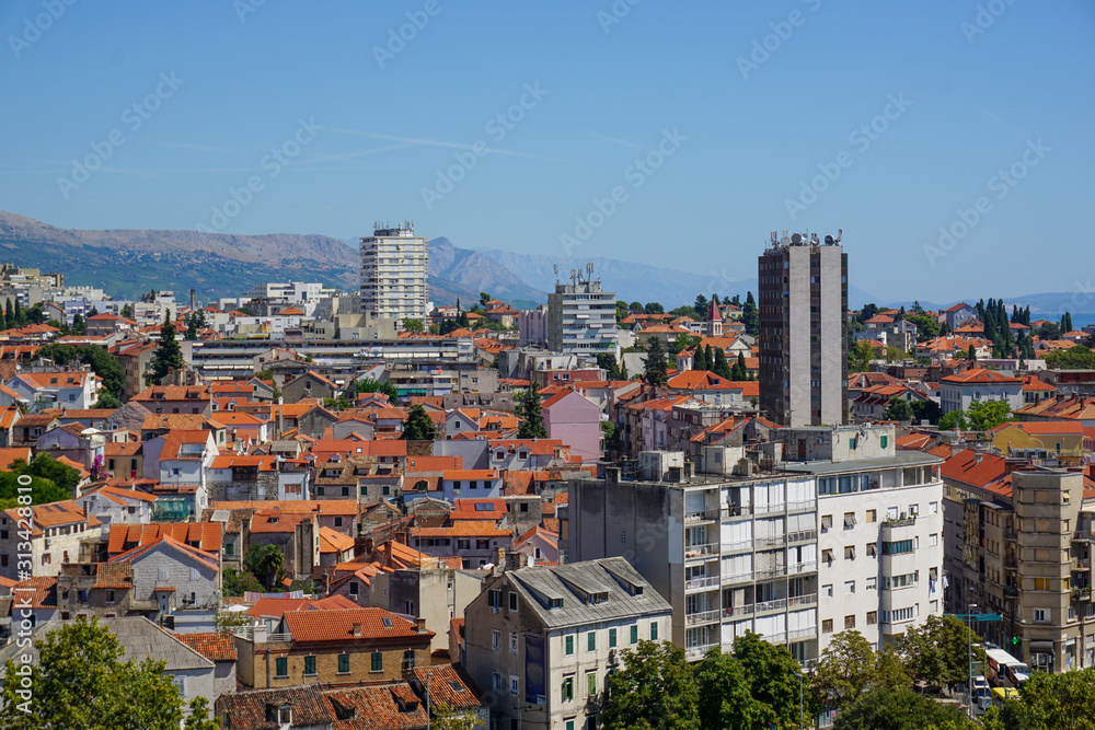 View of the eastern part of Split from the bell tower of the Split Palace. Picturesque mountains, tiled roofs of old houses, modern hotels, a school, a hospital