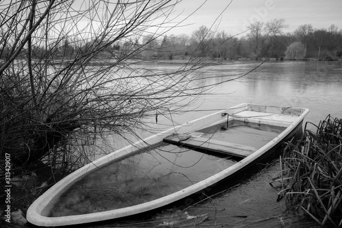 a sunken rowing boat lies on the shore of a frozen small lake