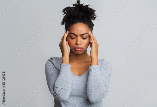 Upset black woman having headache, massaging her temples
