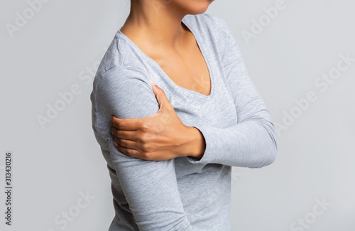 Afro woman holding her forearm over grey background