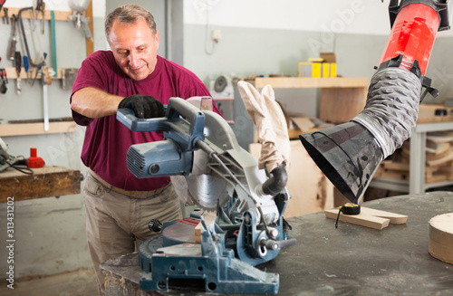 Tableau sur toile Confident workman cutting wooden planks using circular saw