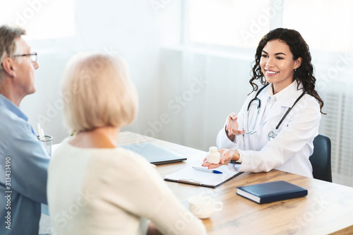 Hispanic doctor consulting elderly couple how to use pill