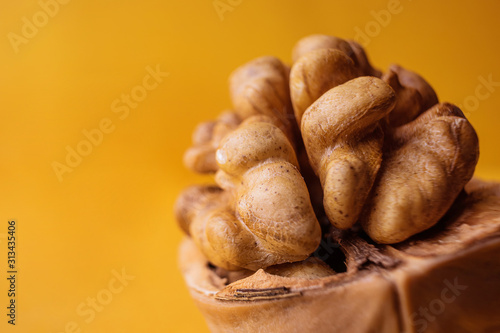 Walnut closeup on a yellow background. Macro photo in warm colors. The concept of wholesome organic food. Copyspace, minimalism.