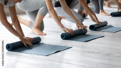 Diverse people folding yoga mat on floor in yoga studio