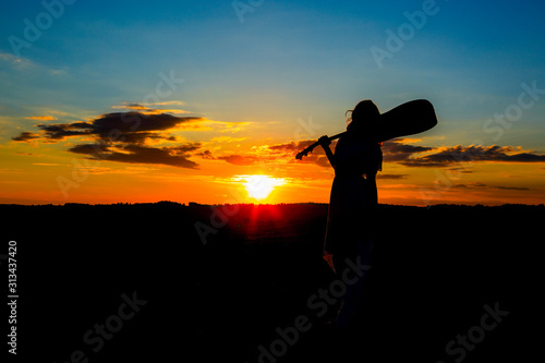 Silhouette woman playing guitar in the sunset