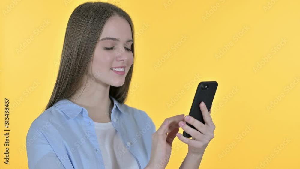 Cheerful Beautiful Woman using Smartphone, Yellow Background Cheerful Beautiful Woman using Smartphone, Yellow Background