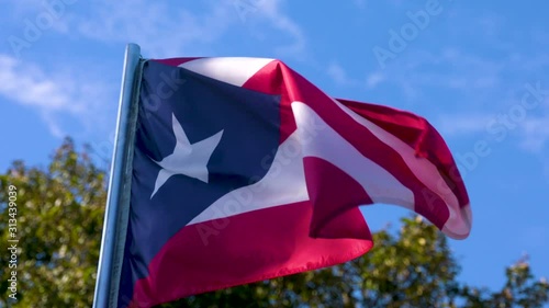 Puerto Rican flag waving in slow motion against a blue sky background. photo