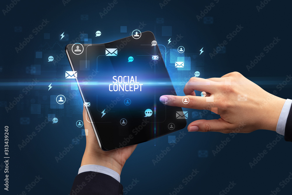 Businessman holding a foldable smartphone with SOCIAL CONCEPT inscription, social networking concept Businessman holding a foldable smartphone with SOCIAL CONCEPT inscription, social networking concept