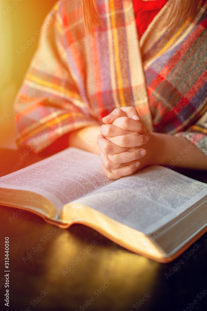 Beautiful woman praying having the Bible opened in front of he Beautiful woman praying having the Bible opened in front of he