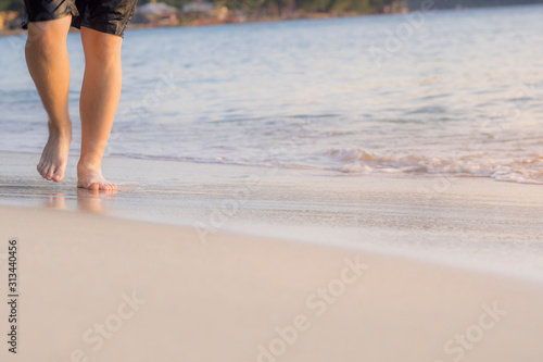 The boy's feet were walking on the beach © noppadon