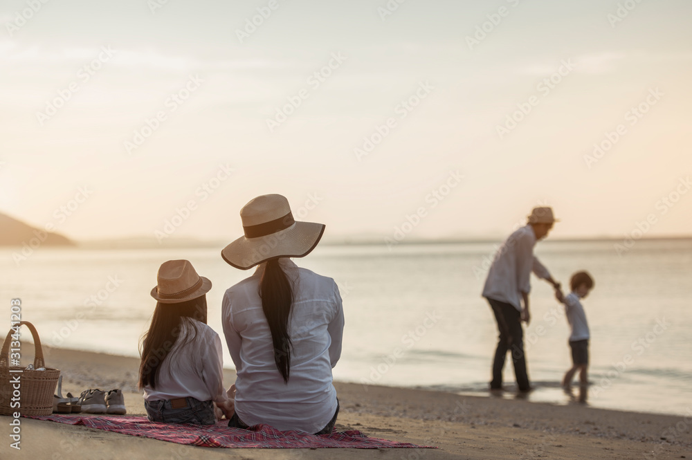 Fototapeta premium Family, travel, beach, relax, lifestyle, holiday concept. Parents and children who enjoy a picnic at the beach on sunset in holiday.