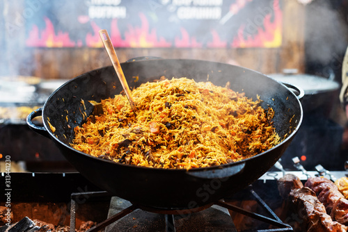 Hot pilaf in large cauldron outdoors. Traditional oriental food. Street food concept. Closeup photo