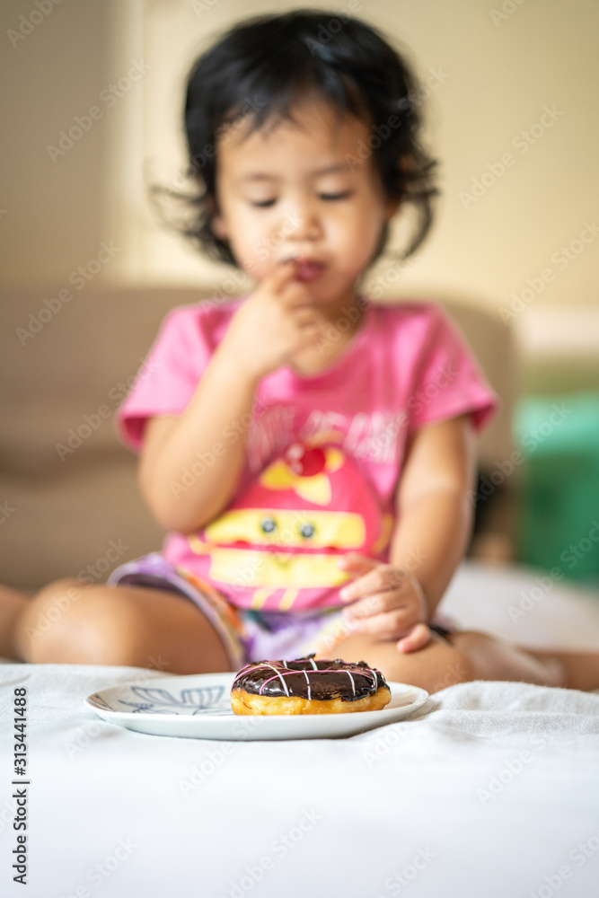 Cute little girl enjoy eating chocolate donut. Cute little girl enjoy eating chocolate donut.
