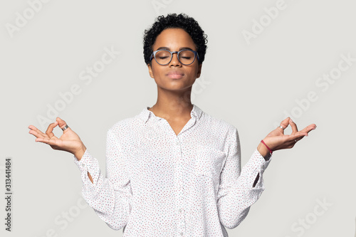 Attractive african woman doing meditation pose isolated on grey background photo