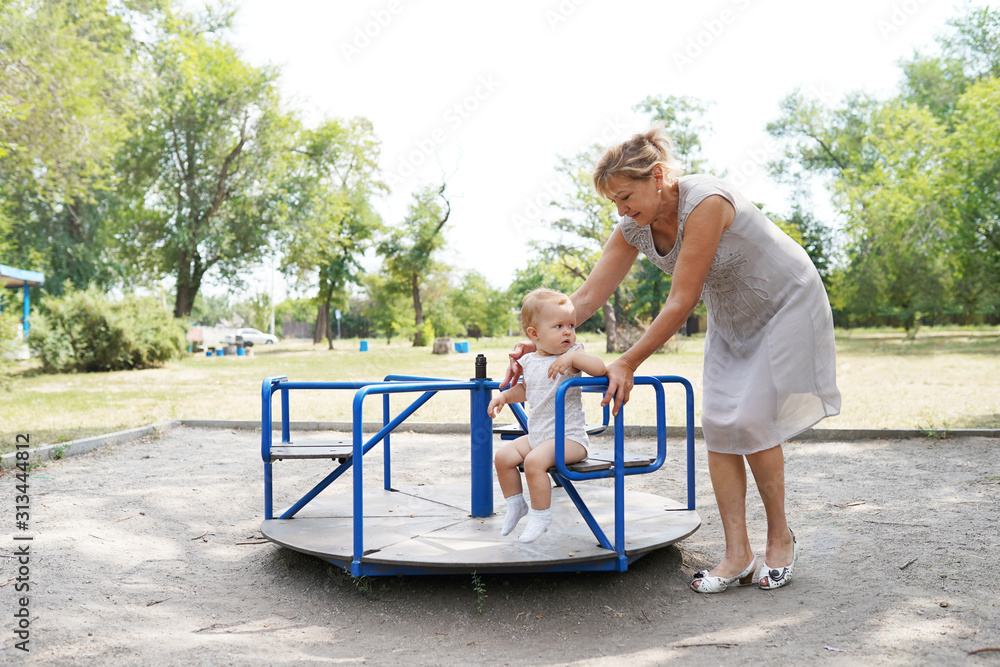 smiling grandmother with baby granddaughter walking in the park smiling grandmother with baby granddaughter walking in the park