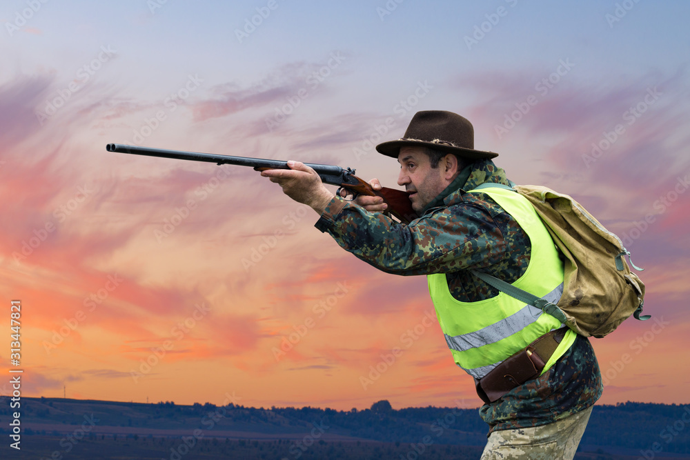 Silhouette of a hunter on the background of the morning red dawn. Stands at the ready with a gun. Silhouette of a hunter on the background of the morning red dawn. Stands at the ready with a gun.