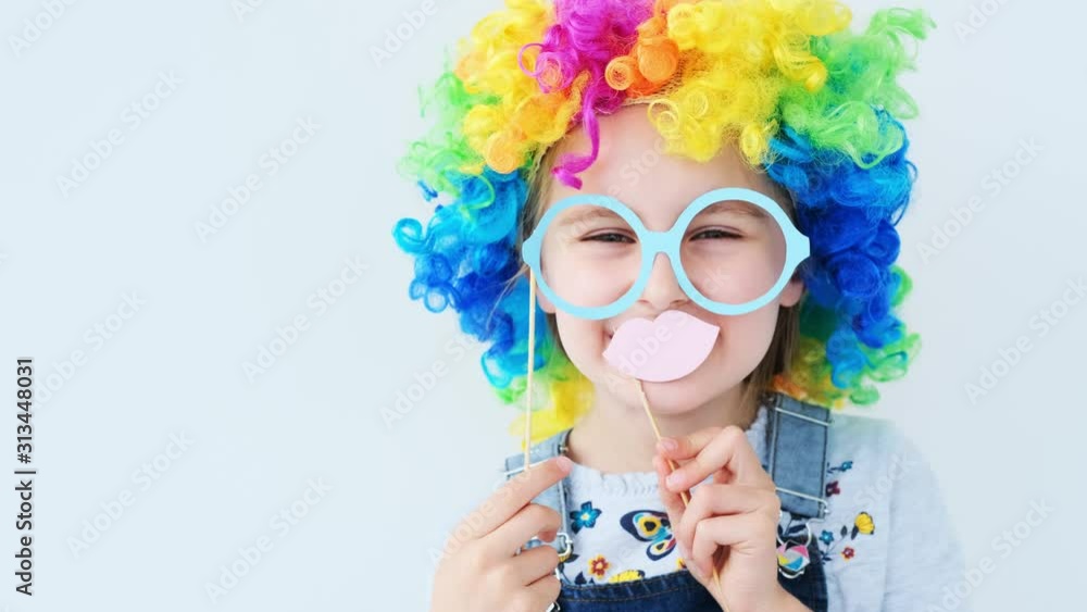 Pretty girl in colored wig holding glasses and lips on stick near her face Pretty girl in colored wig holding glasses and lips on stick near her face