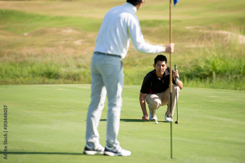Two Asian man golfer aiming  golf ball  at golf course