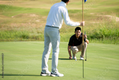 Two Asian man golfer aiming golf ball at golf course