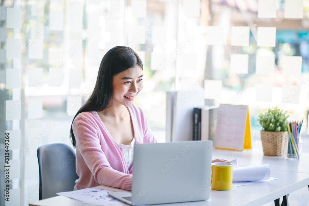 Confident happiness young woman working on laptop or notebook in her office. Beautiful Freelancer Woman working online at her home. Beauty Asian business woman concept. Confident happiness young woman working on laptop or notebook in her office. Beautiful Freelancer Woman working online at her home. Beauty Asian business woman concept.