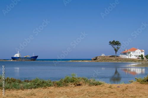 The sunny landscape of seaside with ship and little white house at Cyprus 