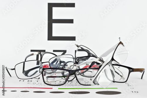 Glasses on a white background. Background with letters for vision test. Many glasses are dropped.