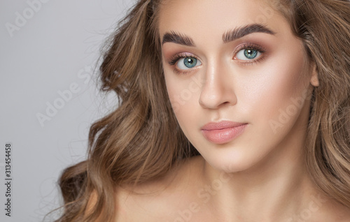 Portrait of a beautiful woman with long eyelashes, beautiful fresh nude make-up, thick eyebrows and with clean skin in a beauty salon. Eyelash extensions. Face close-up.Make-up and cosmetology concept