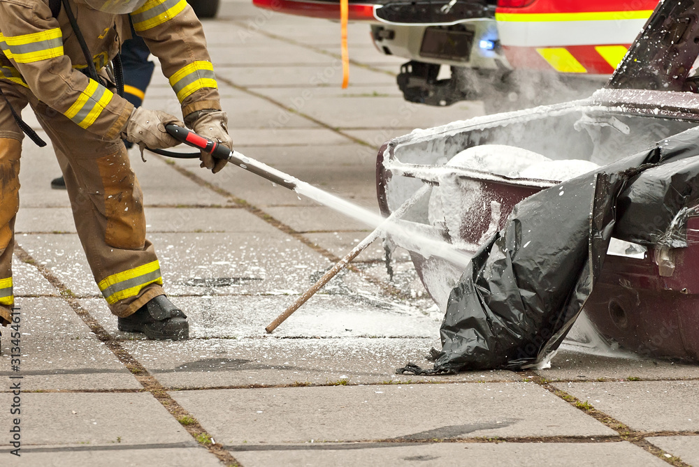 The fireman extinguishes the burned car. Training firefighters. Demonstration rescue work.