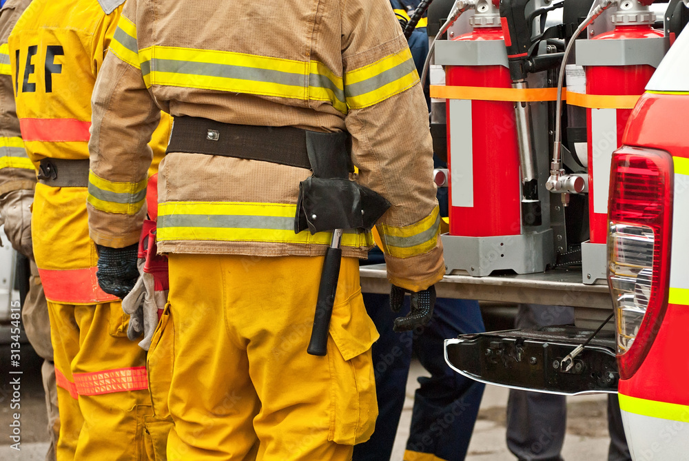 Firefighter on a background of a machine with fire equipment. Preparation for rescue work. Rescuers demonstrate skills. Demonstration training of the fire brigade team. Firefighter on a background of a machine with fire equipment. Preparation for rescue work. Rescuers demonstrate skills. Demonstration training of the fire brigade team.