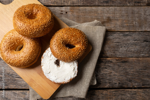 Vászonkép Sesame bagels with spreadable cream cheese on wooden background