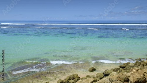 Beautiful colorful water near beach during low tide with big waves behind reef in ocean