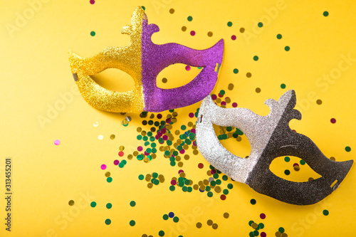 A festive, colorful group of mardi gras or carnivale mask on a yellow purple background. Venetian masks. photo