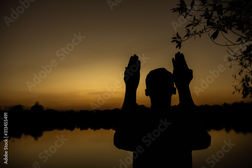 Silhouette Young asian muslim man praying on sunset,Ramadan festival concept