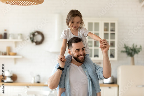 Fotografie Father carrying on shoulders little daughter having fun at home