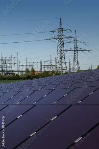 Solar power plant. Solar panels in the foreground, transformer station and power pylons in the background