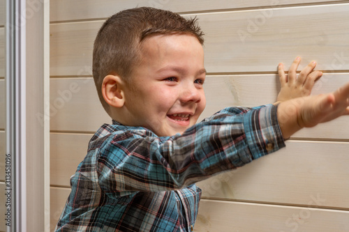 Bild auf Leinwand A 4 years old boy in a blue clerical shirt is crying on a light wooden background