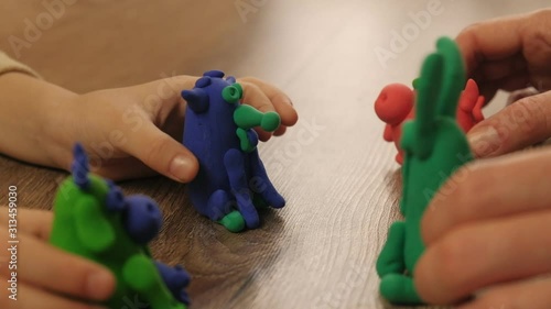 Child and mother with colorful plasticine toy, kid hand, woman clay.