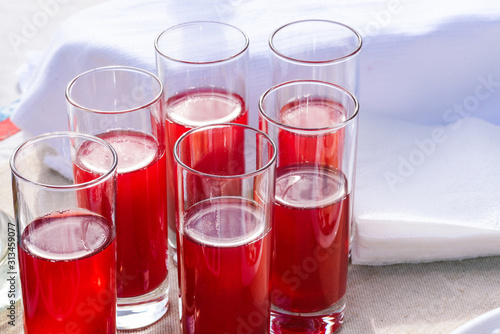Glass glasses with a drink of red color. Colorful cocktail. Glasses of wine on a white table. Soft and alcoholic drinks