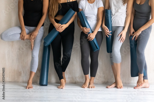 Group diverse sporty women with yoga mats standing in gym