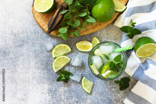 Summer cold drink and cocktail. Fresh Mojito cocktail with lime, ice and mint in a glass on a gray stone background.Top view flat lay background. Copy space.