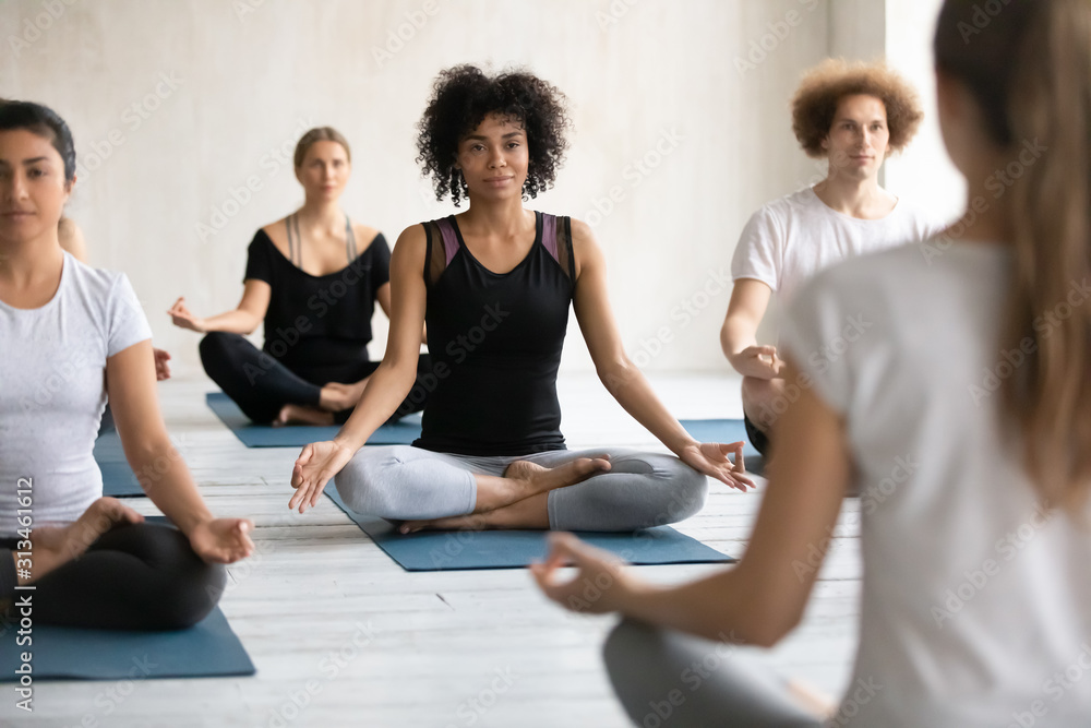 Female coach training diverse people, practicing yoga, doing Padmasana exercise Female coach training diverse people, practicing yoga, doing Padmasana exercise
