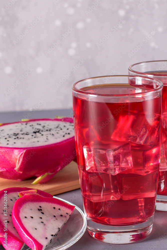 Glass of mango dragonfruit refresher drink on grey table with ice cubes. Copy space. Glass of mango dragonfruit refresher drink on grey table with ice cubes. Copy space.
