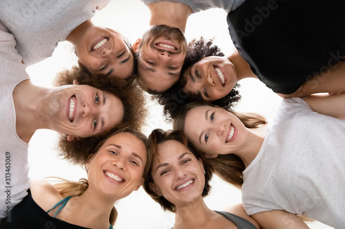 Low angle smiling diverse people standing in circle, celebrating success