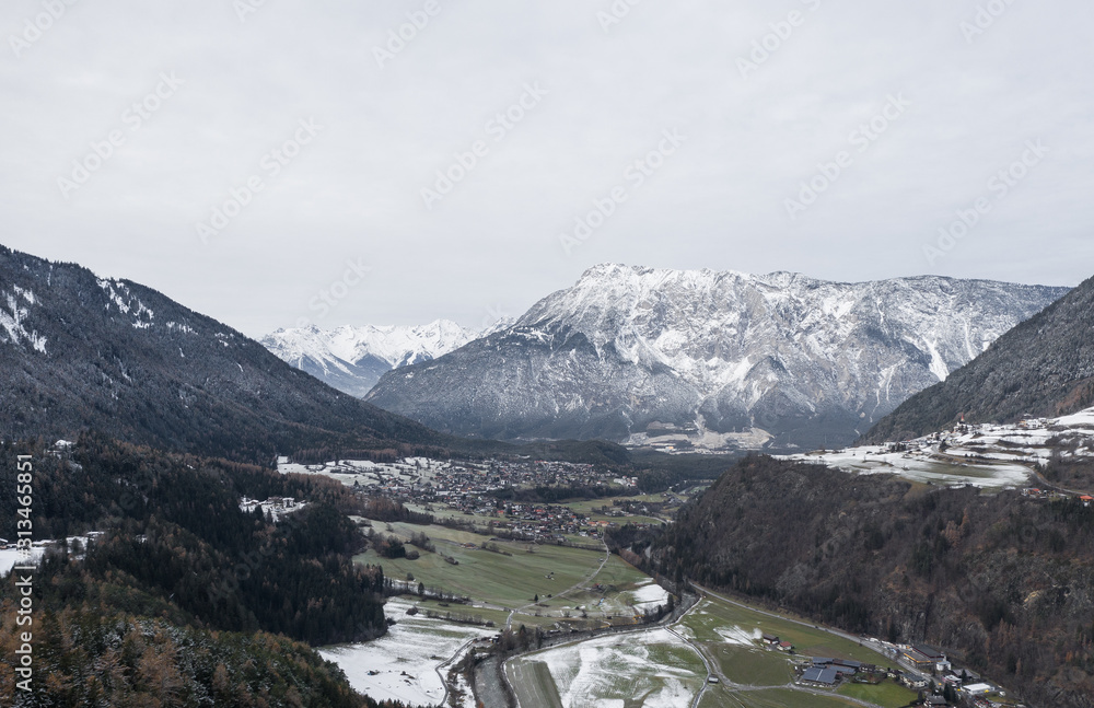 Winter mountains panorama with ski slopes. Drone flight through dramatic, snowy winter mountain range. Aerial landscape of the Alps in Europe during winter season with fresh snow. Austria.