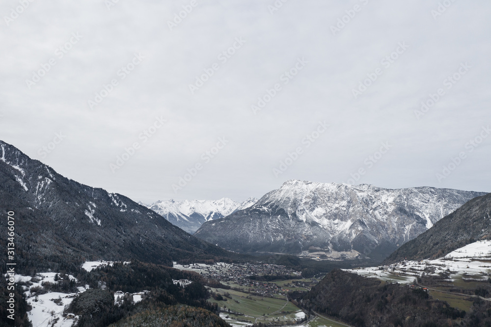Winter mountains panorama with ski slopes. Drone flight through dramatic, snowy winter mountain range. Aerial landscape of the Alps in Europe during winter season with fresh snow. Austria.